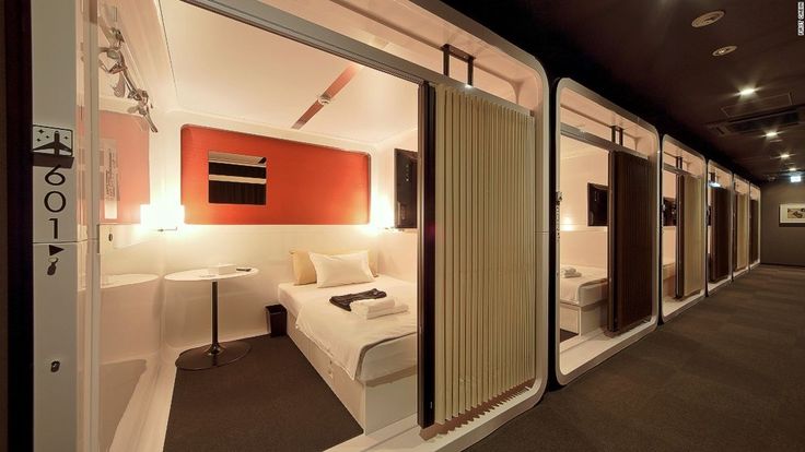 a room with two beds and mirrors on the wall, in front of a door