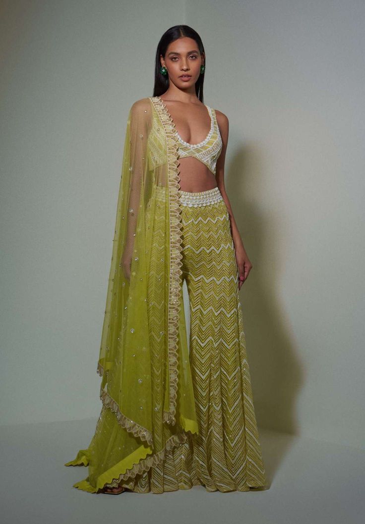 Editor's Note Our Lime Green Ivory And Gold Cutwork Bustier Paired With Our From The Top V-v Sharara And Heavy Dupatta. Color: Lime Green Fabric: Net, Crepe, Double Georgette Embroidery Details: Bead, Thread, Resham, Sequin, & Bugel Care: Dry Clean Only About the Designer Ritika Mirchandani is known for its clothes that are wearable and luxurious with a feminine and glamorous feel to them. Net Sharara Designs, Green Indian Outfit, Ritika Mirchandani, Green Sharara, Embroidered Bustier, Sheer Dupatta, Sharara Designs, Heavy Dupatta, Haldi Outfits