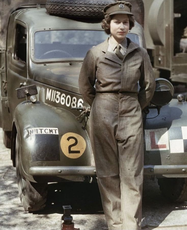 a woman in uniform standing next to an old truck