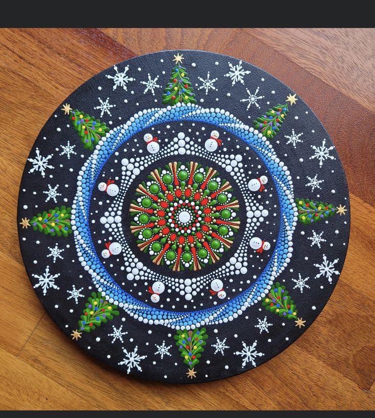 a black plate with christmas decorations painted on the inside and around it, sitting on a wooden surface