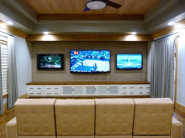 a living room with three televisions mounted on the wall and two couches facing each other