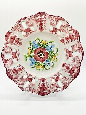 an ornate red and white plate with flowers on it's rim, in the shape of a flower