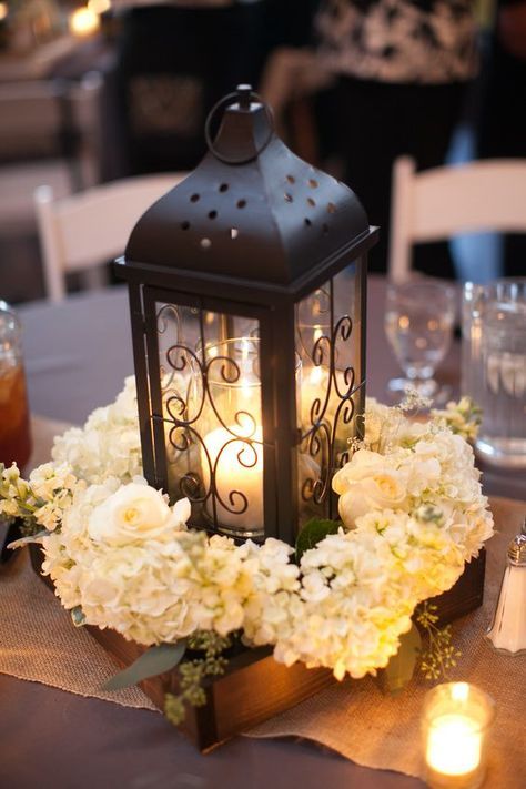 a lantern with flowers and candles on a table