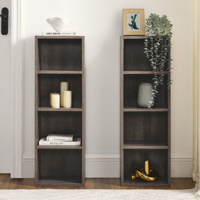 two wooden bookshelves with candles on them in front of a white door and rug