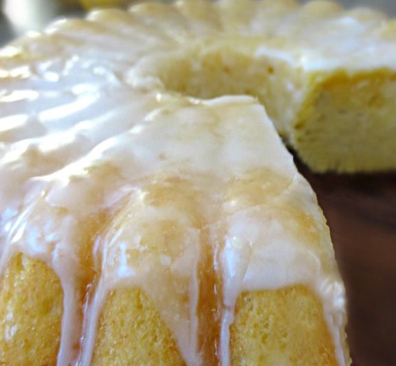 a bundt cake with white icing sitting on top of a wooden cutting board