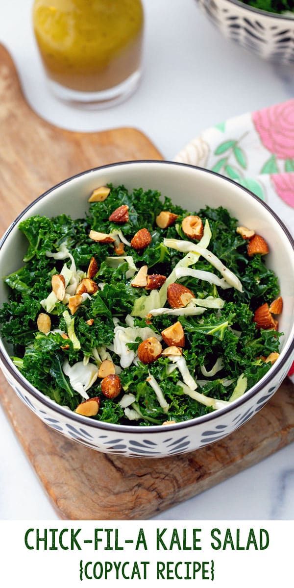 a bowl filled with kale salad on top of a wooden cutting board