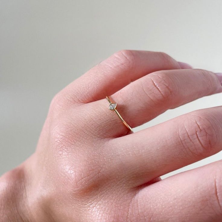 a woman's hand with a gold ring on it and a diamond in the middle