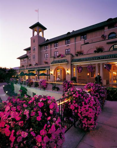 the hotel is lit up at night with pink flowers on the balcony and green umbrellas