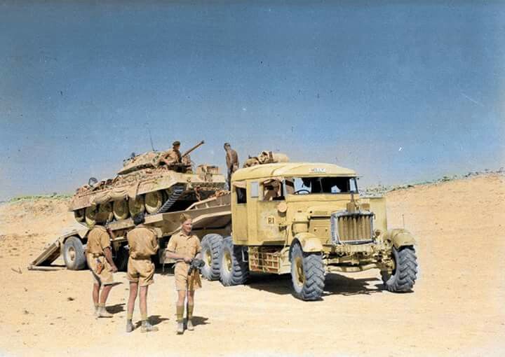 two men standing in front of an army truck