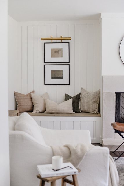 a living room filled with furniture and a clock on the wall above it's fireplace