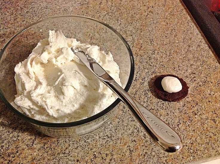 a glass bowl filled with whipped cream next to an oreo cookie on a counter