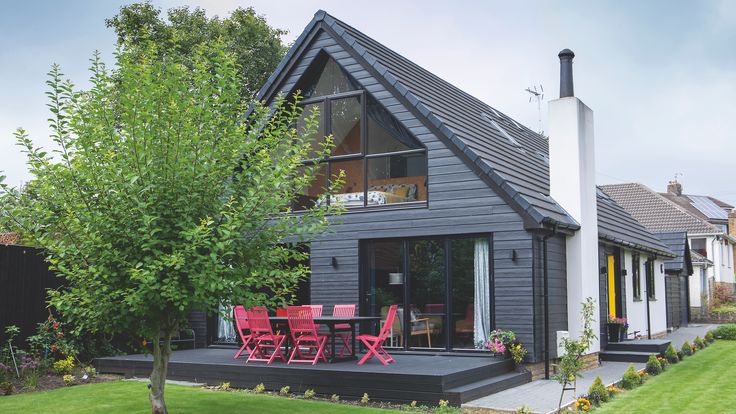 a black house with red chairs in the front yard