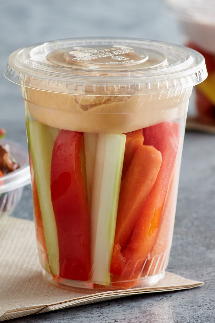 a plastic cup filled with sliced vegetables on top of a table