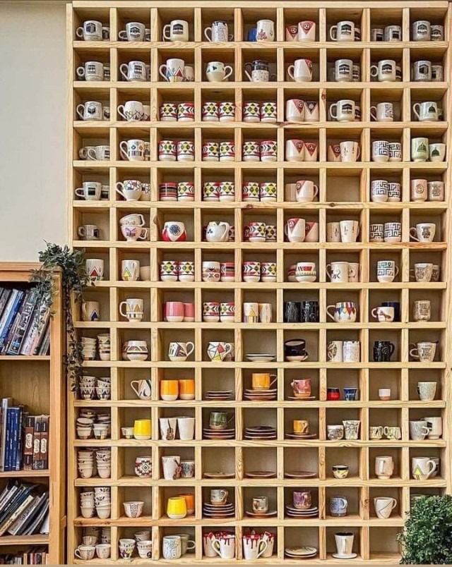 a wooden shelf filled with lots of cups and saucers