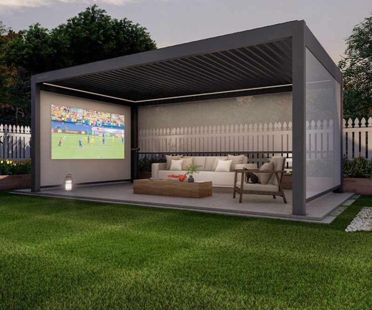 an outdoor living area with couches and a projector screen on the side of it