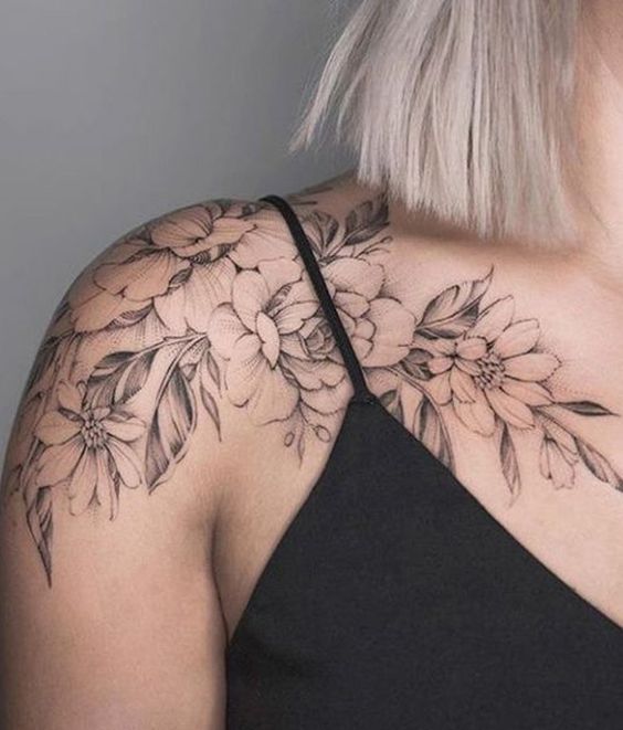 a woman's shoulder with flowers and leaves on the back of her neck,