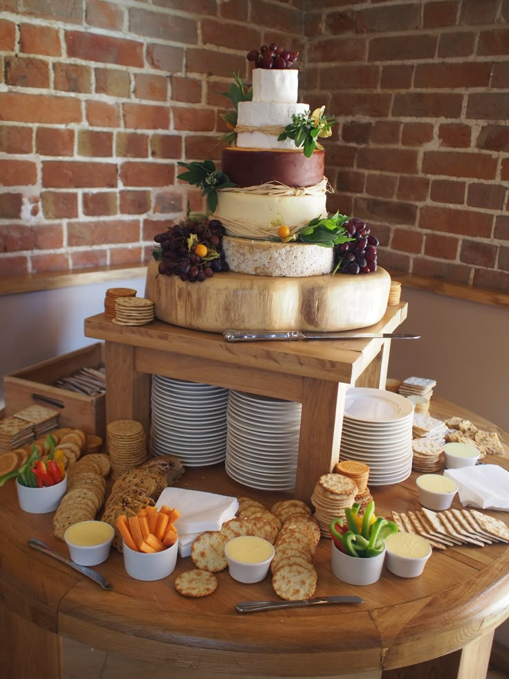 a table topped with lots of food next to a brick wall and a wooden table