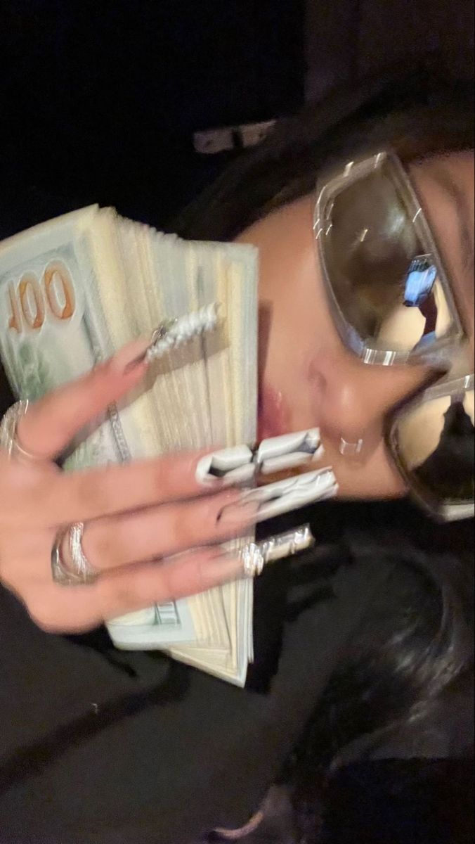 a woman wearing sunglasses and holding money in her hand