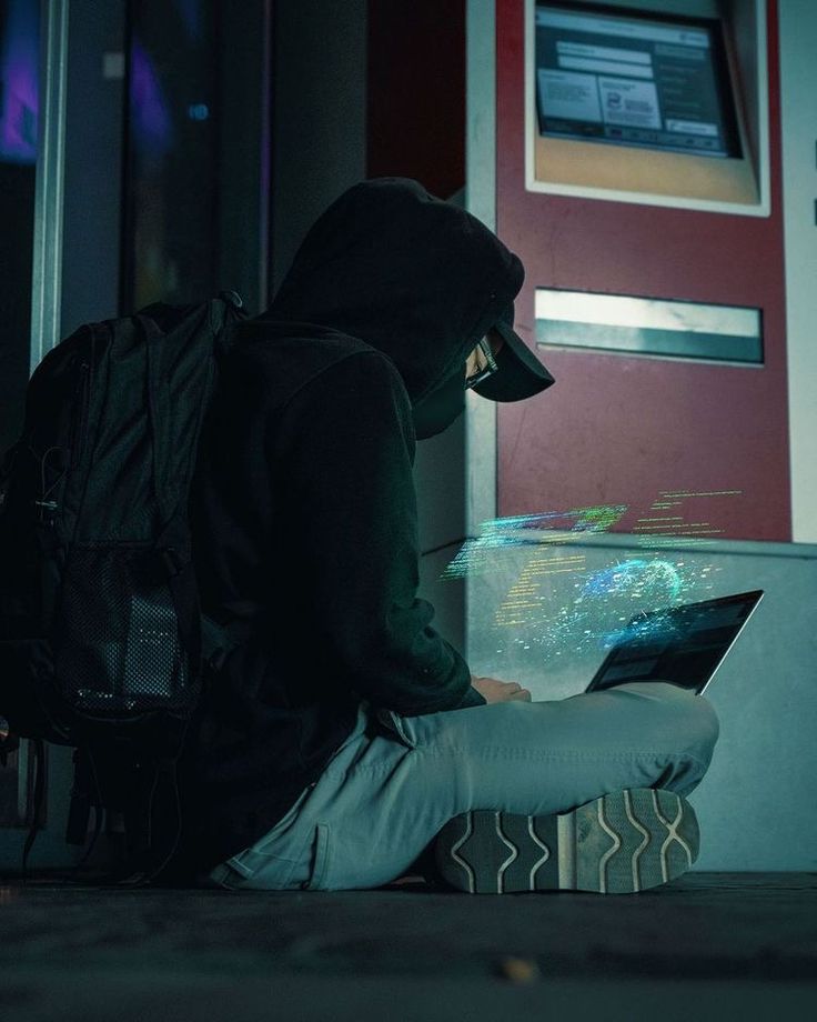 a person sitting on the ground with a laptop computer in front of their back pack