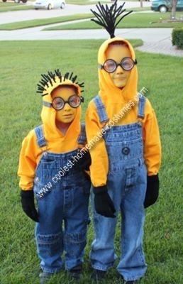 two children dressed in yellow and blue overalls standing next to each other on grass