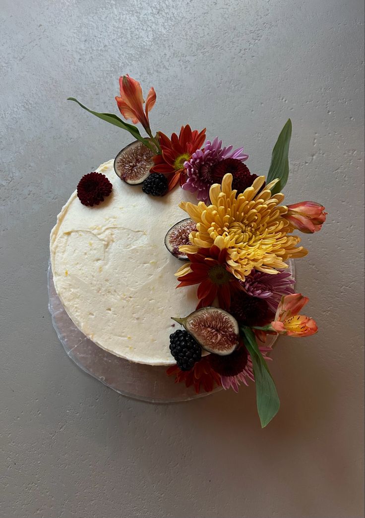 a cake decorated with fresh flowers and figs