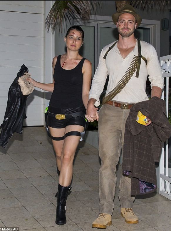 a man and woman dressed in costumes walking down the street holding hands with each other