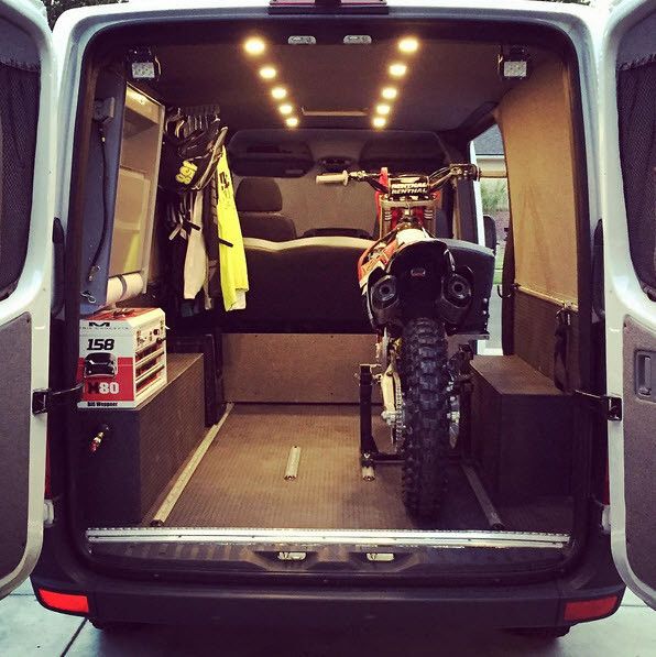 the back end of a van with an atv and bike in it's cargo area