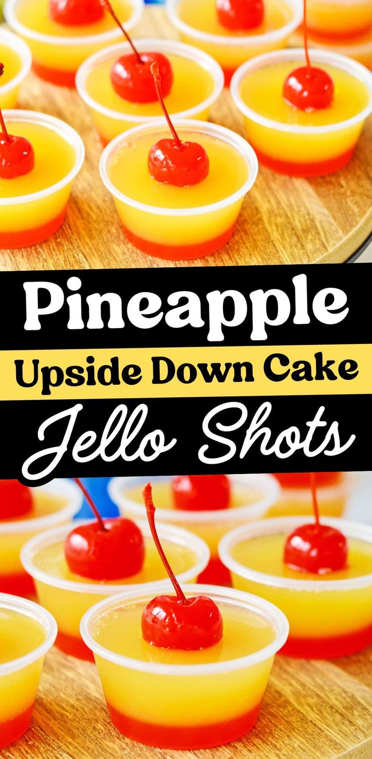 pineapple upside down cake jello shots with cherries in small cups on a wooden tray