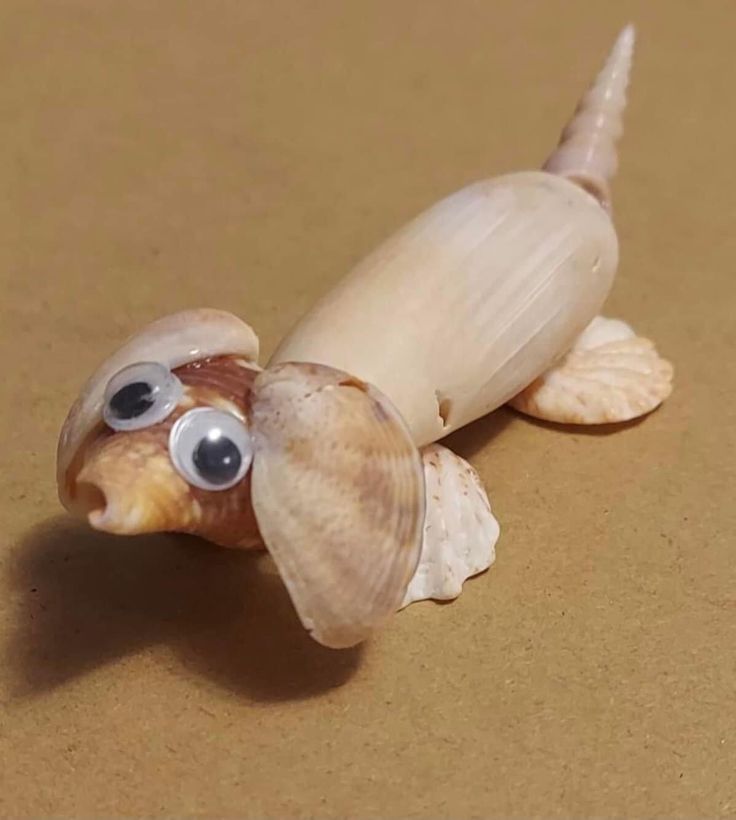 a small toy turtle with googly eyes on it's head and tail, sitting on a brown surface