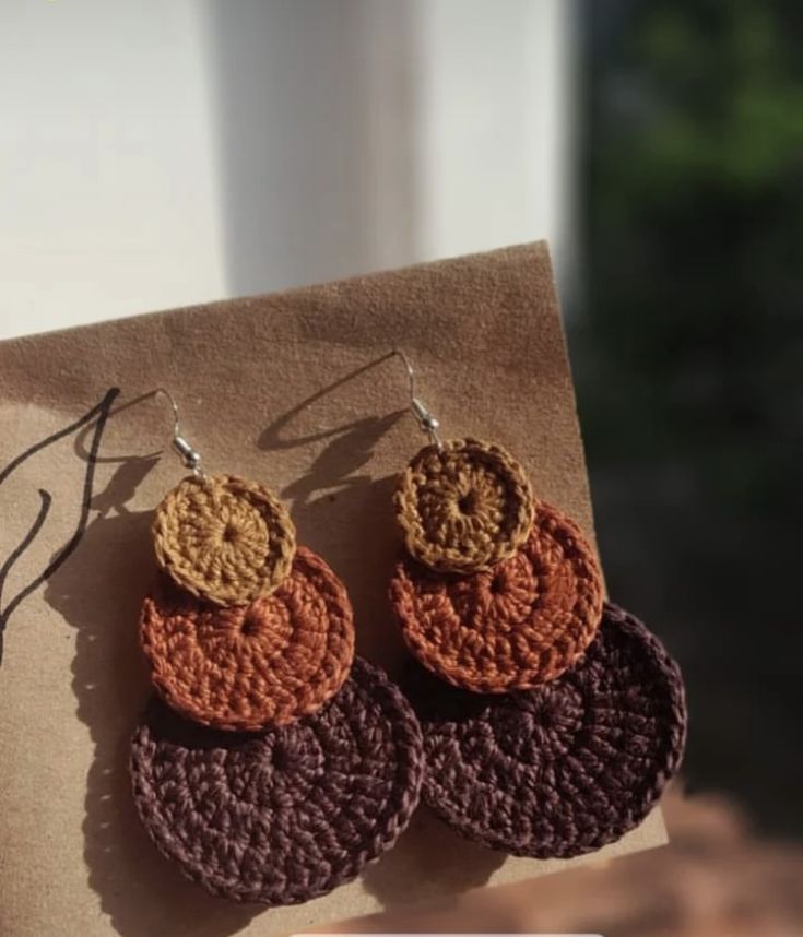 two pairs of crocheted earrings on top of a piece of brown and orange paper