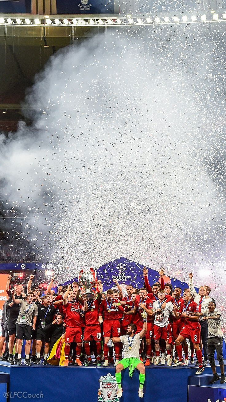 a group of people standing on top of a soccer field holding up a trophy and confetti