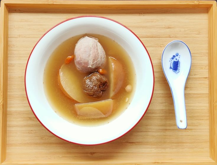 a bowl of soup and spoon on a wooden tray