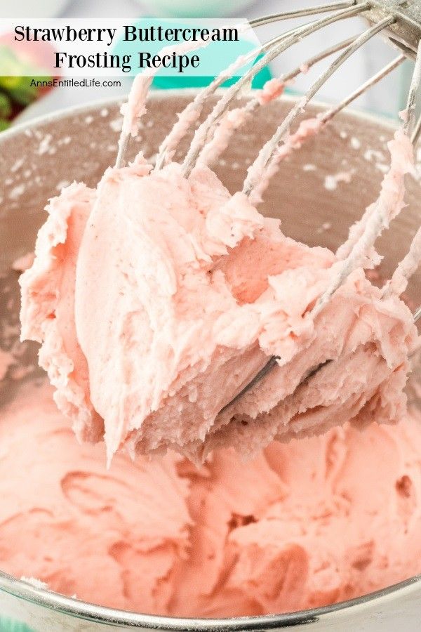 a metal bowl filled with pink frosting and a whisk in the middle