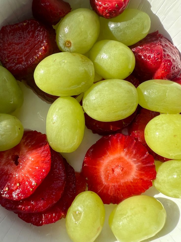 grapes and strawberries are arranged in a bowl