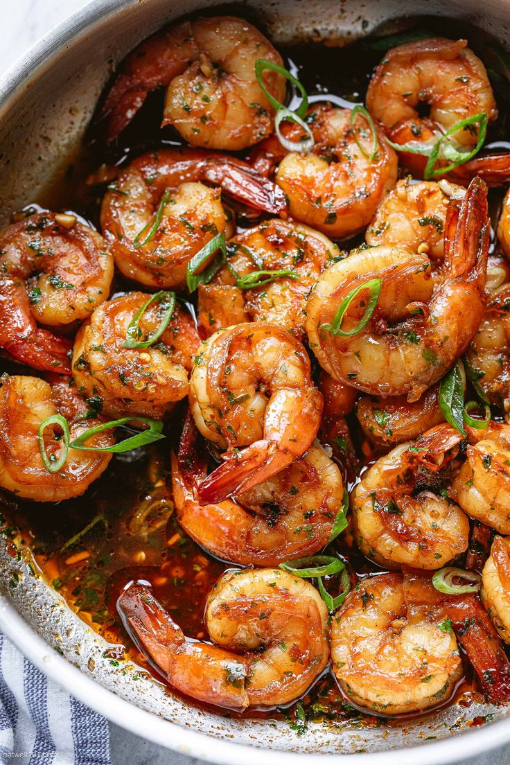 cooked shrimp with sauce in a pan on a wooden table