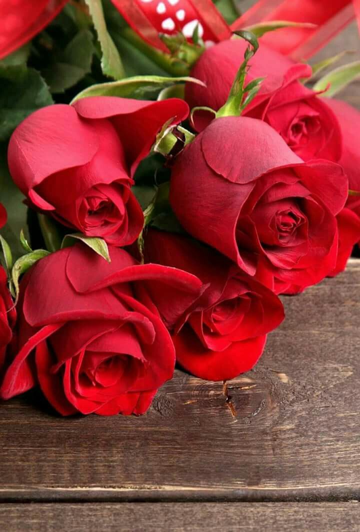 a bunch of red roses sitting on top of a wooden table