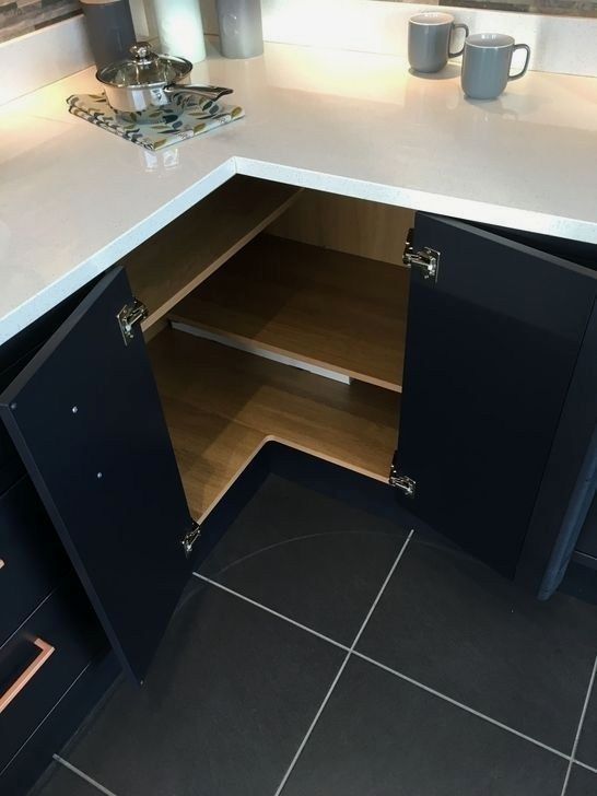 an open cabinet in the middle of a kitchen counter top with coffee mugs on it