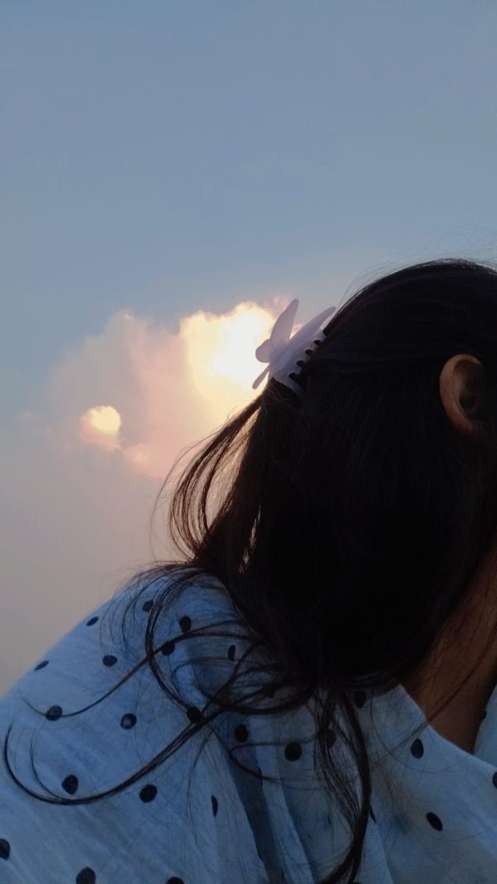 a girl is looking at the sky with clouds in the background