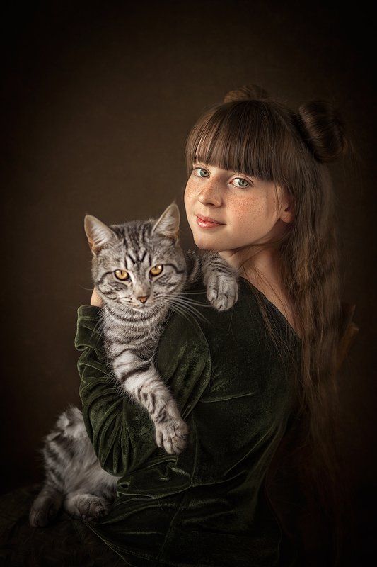 a woman holding a cat in her arms and looking at the camera with an intense look on her face