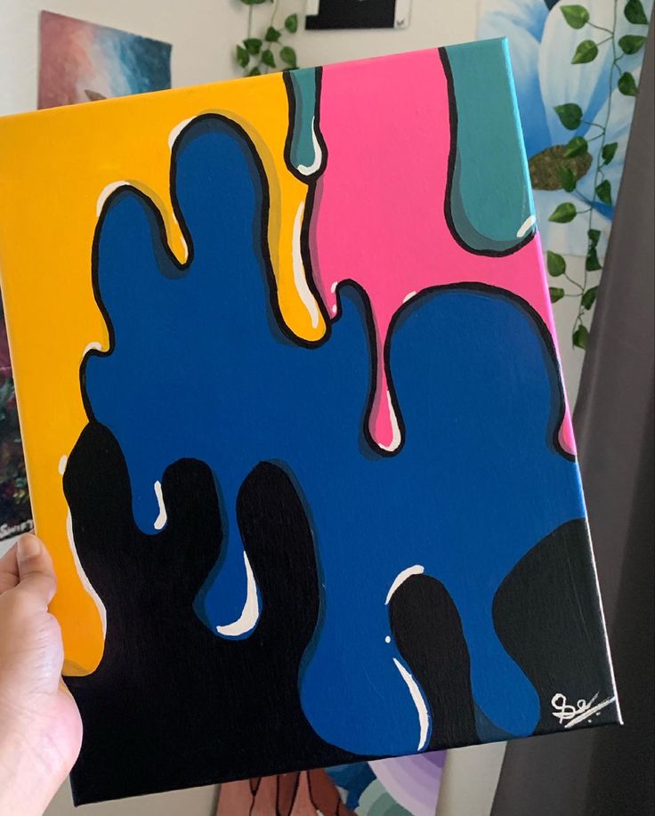 a person holding up a piece of art that has been painted with different colors and shapes