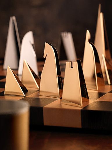 several gold and silver trophies sitting on top of a chess board