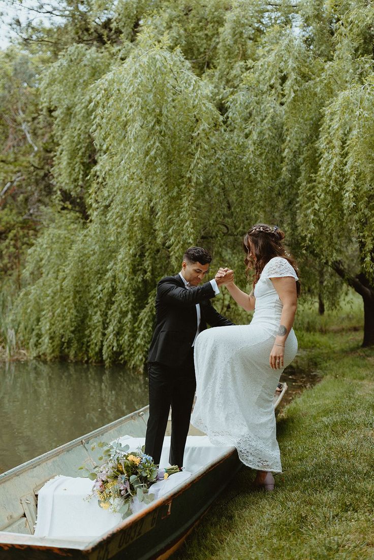 a bride and groom standing on the edge of a boat