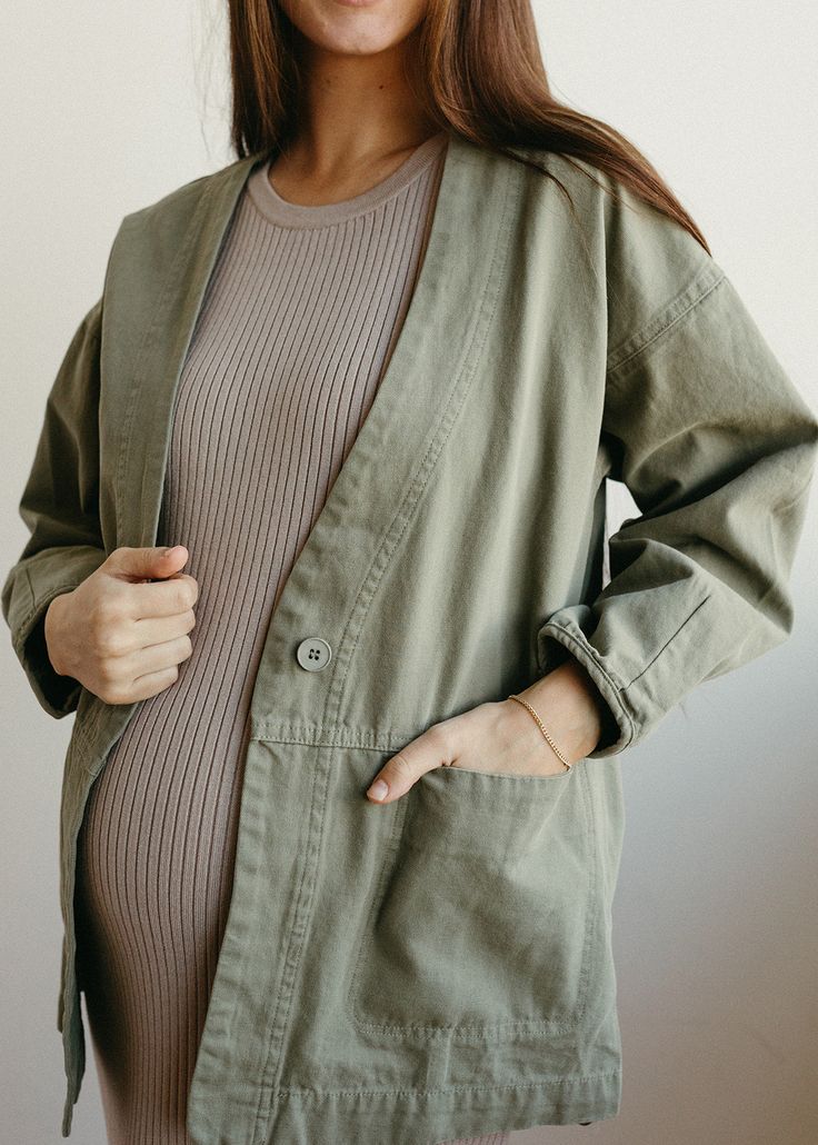 The Evergreen Jacket is a feminie canvas jacket with a relaxed fit and button front closure. This jacket is a stylish finishing peice to any outfit in a beautiful sage green color. Model is 5'8" wearing a size small Pregnant model is 5'9" in 3rd trimester, wearing a size medium Olive Cotton Outerwear For Fall, Khaki Cotton Outerwear For Layering, Olive Cotton Utility Jacket For Fall, Olive Cotton Button-up Outerwear, Olive Button-up Cotton Outerwear, Green Relaxed Fit Utility Jacket For Fall, Green Relaxed Fit Utility Jacket With Button Closure, Green Utility Jacket With Button Closure, Green Utility Jacket With Button Closure And Relaxed Fit