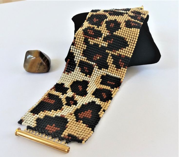 the beaded tie is next to a gold object on a white table with a black background