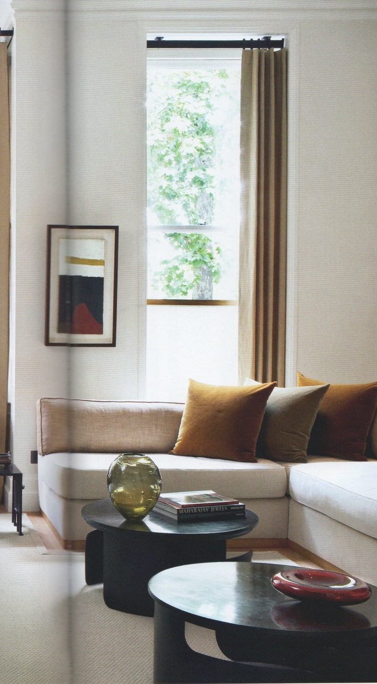 a living room filled with furniture next to a window covered in brown and white curtains