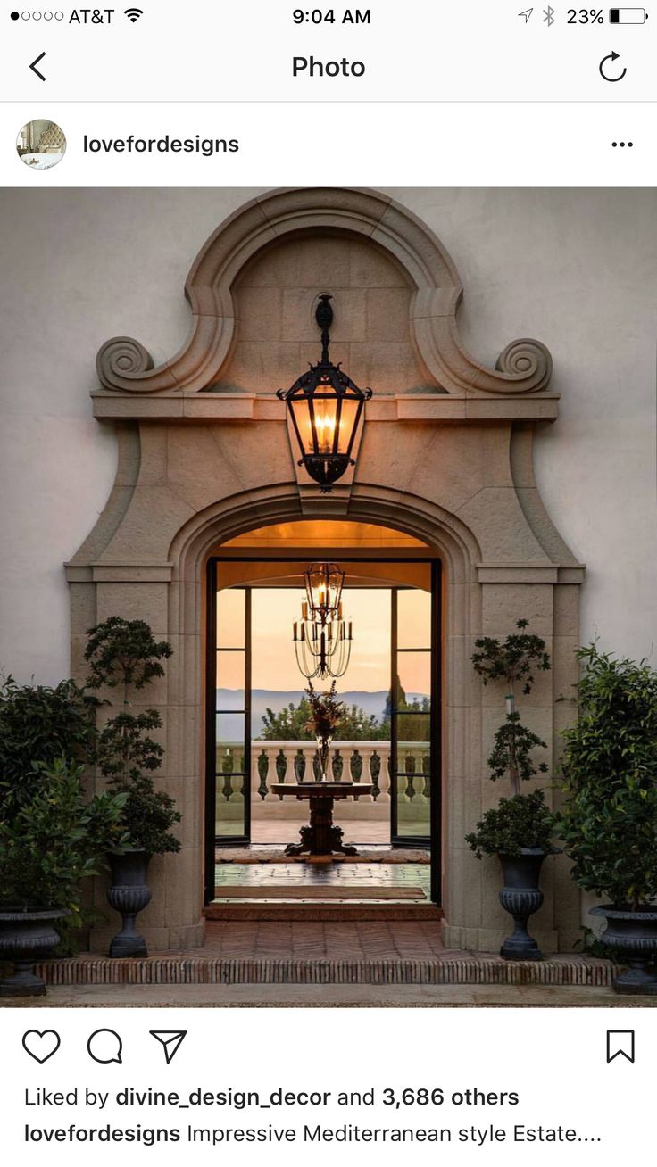 an entrance to a building with a fountain in the center and potted plants on either side