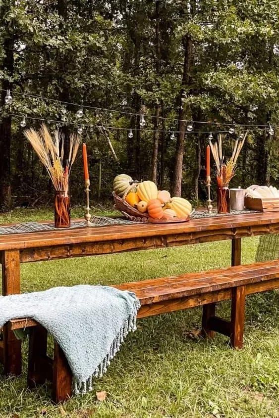 a picnic table with pumpkins and candles on it