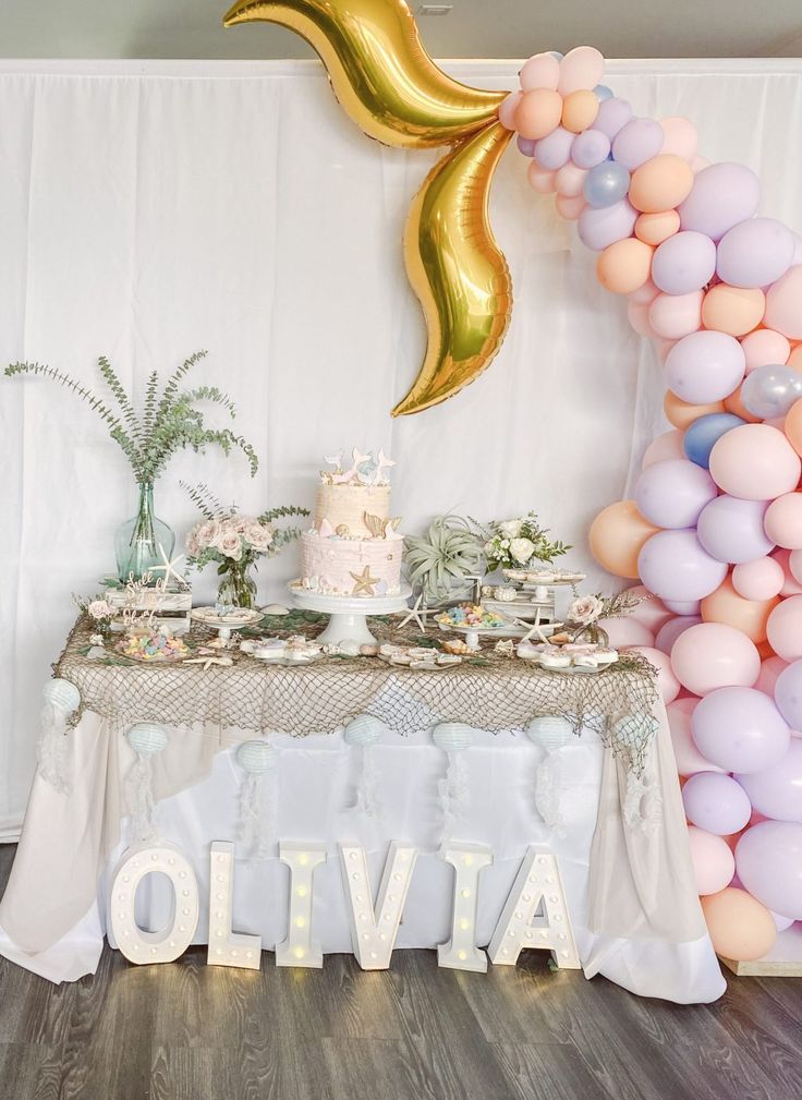 a table topped with a cake and balloons