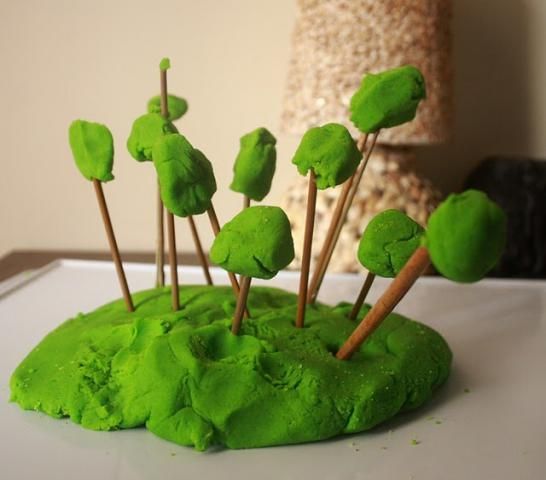 green cake with sticks sticking out of it's top and trees in the middle