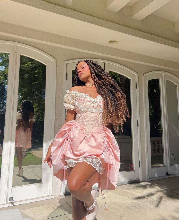 a woman in a pink dress is standing outside